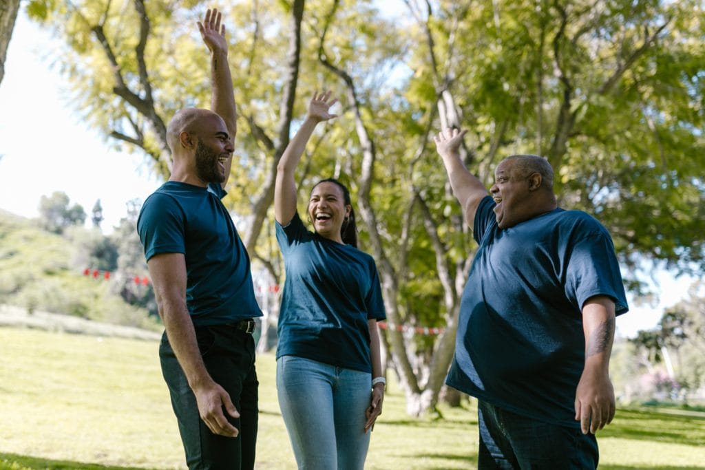 Employees In Blue T-Shirts With Arms Raised 