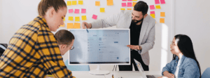 Man Explaining Employee Coaching Plan on Screen to Colleagues