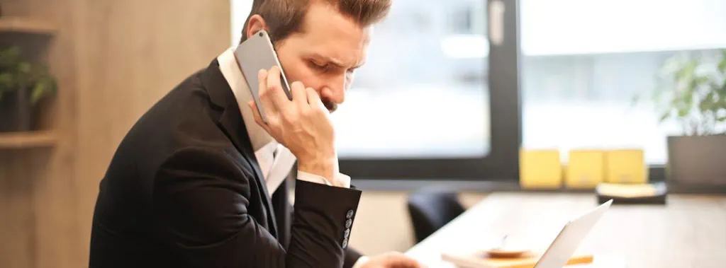 Man in Suit Making a Phone Call in Front of Laptop
