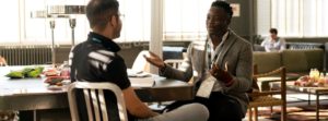 Two Men Wearing Lanyards Having Conversation in Office