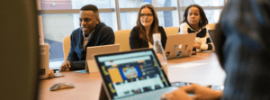 Group of Employees Sitting Around Board Table With Laptops