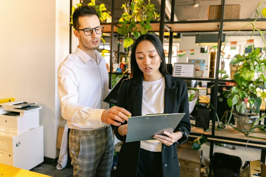 Manager and Employee Reading From Notepad in Office