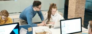 Positive Leader Guiding Employee Through Task on Laptop