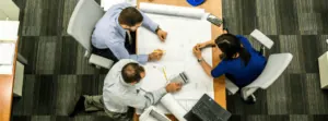 Three People Reviewing HR Data Analytics Worksheets on Table